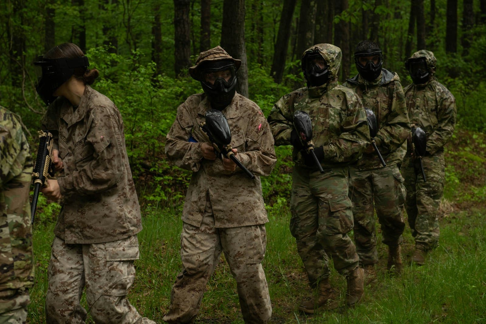 Paintball squad in camouflage gear walking through the woods