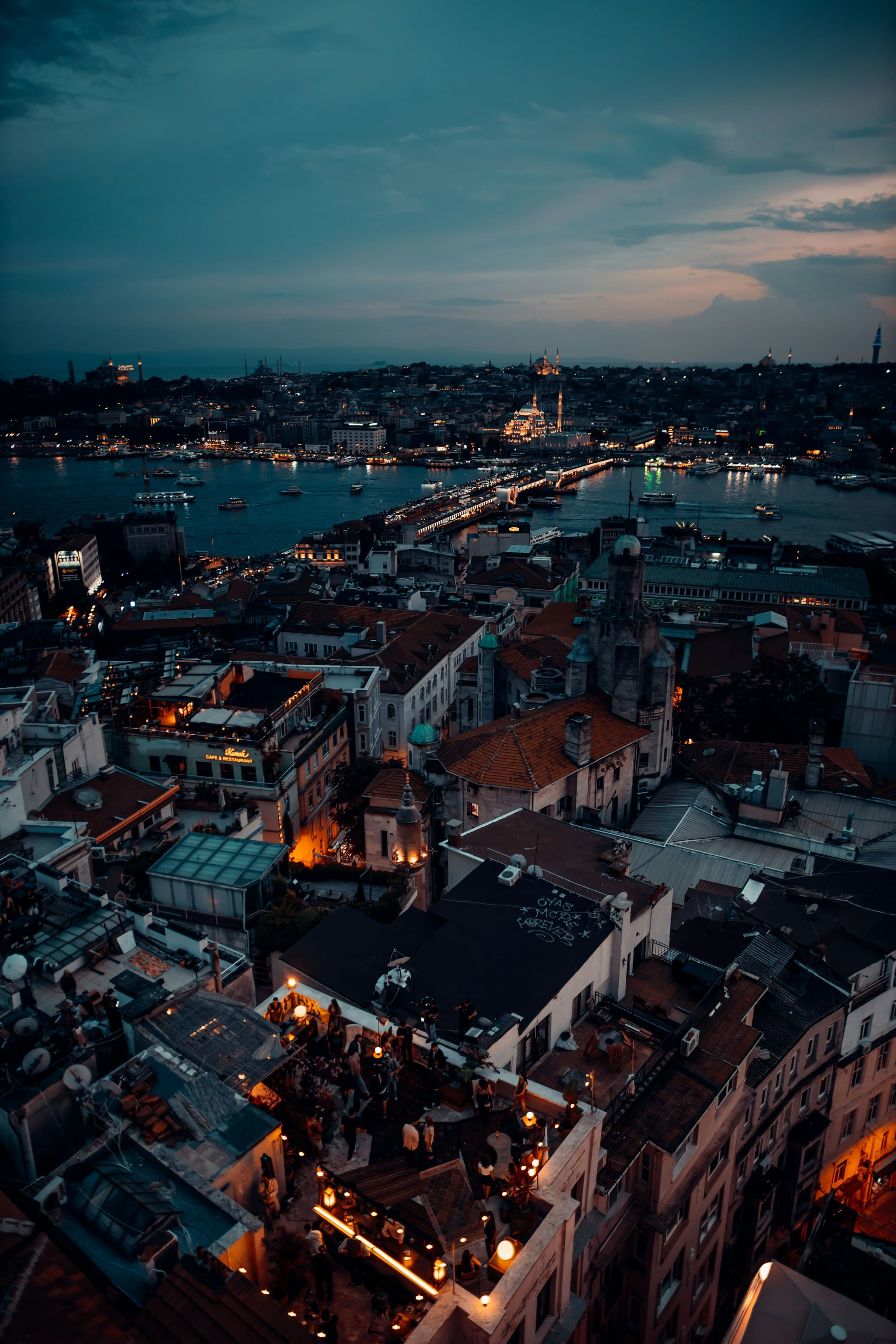 Istanbul rooftops at blue hour viewed from Galata: the Golden Horn, mosque silhouettes, and rooftop lights